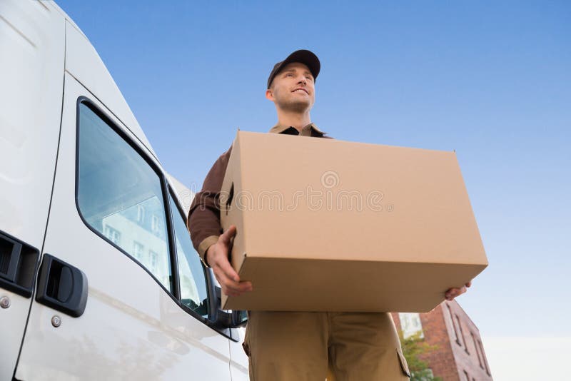 Caja de cartón del hombre de entrega que lleva en camión contra el cielo fotos de archivo Caja de cartón del hombre de entrega que lleva en camión contra el cielo fotos de archivo