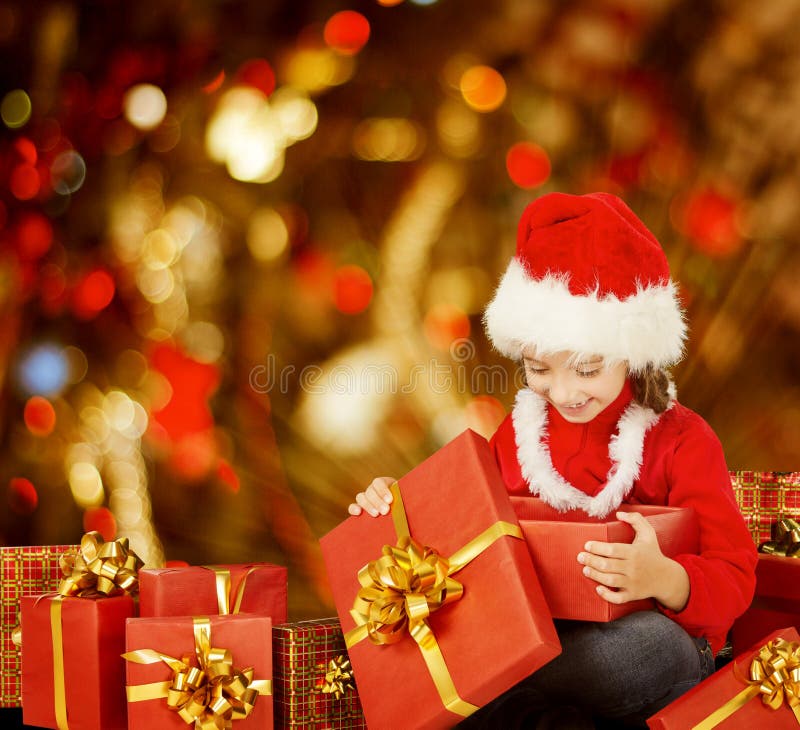 Caja de regalo de apertura del niño de la Navidad actual, niño feliz en Santa Hat imágenes de archivo libres de regalías Caja de regalo de apertura del niño de la Navidad actual, niño feliz en Santa Hat imágenes de archivo libres de regalías