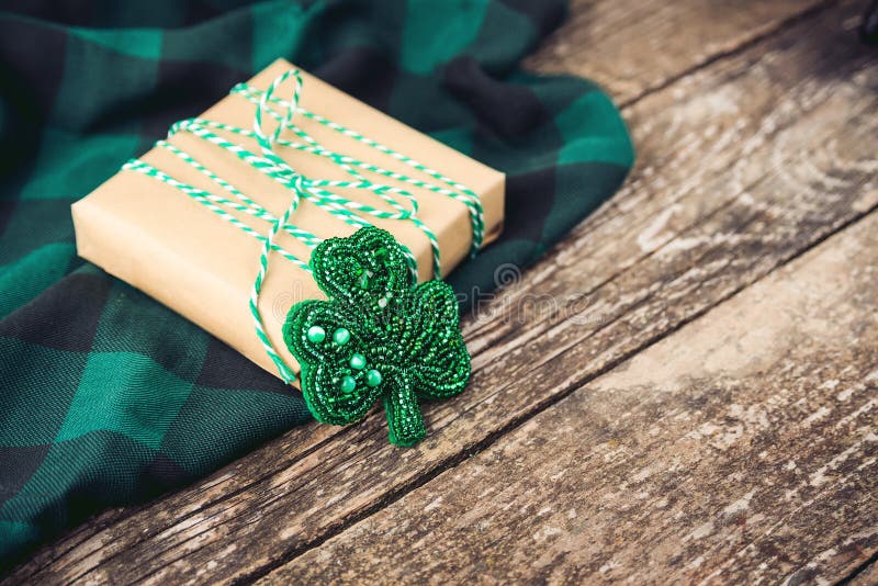 Caja de regalo elegante con la broche verde de la cuerda y del trébol, en fondo rústico de madera imagen de archivo libre de regalías Caja de regalo elegante con la broche verde de la cuerda y del trébol, en fondo rústico de madera imagen de archivo libre de regalías