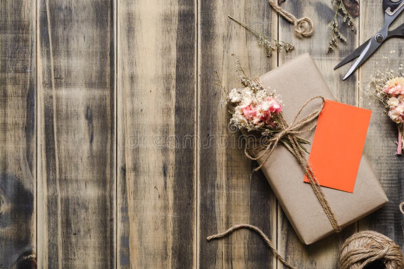 Caja de regalo envuelta en papel del arte hecho a mano hermoso de DIY con la tarjeta anaranjada del espacio en blanco en fondo de foto de archivo libre de regalías Caja de regalo envuelta en papel del arte hecho a mano hermoso de DIY con la tarjeta anaranjada del espacio en blanco en fondo de foto de archivo libre de regalías
