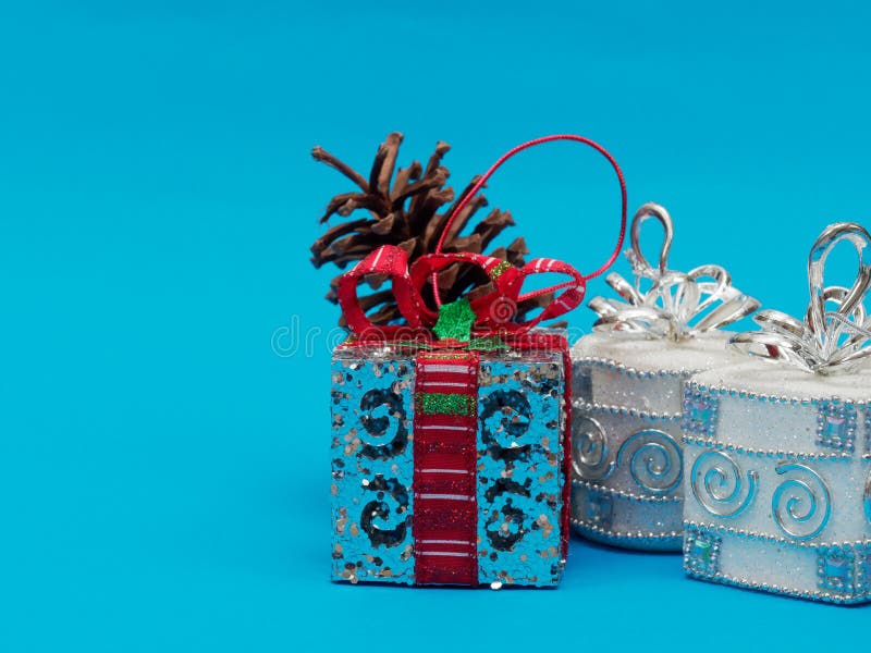 Caja de regalo de plata brillante blanca con la cinta roja y arco con el cono de plata de la caja y del pino de la casilla blanca fotografía de archivo libre de regalías Caja de regalo de plata brillante blanca con la cinta roja y arco con el cono de plata de la caja y del pino de la casilla blanca fotografía de archivo libre de regalías