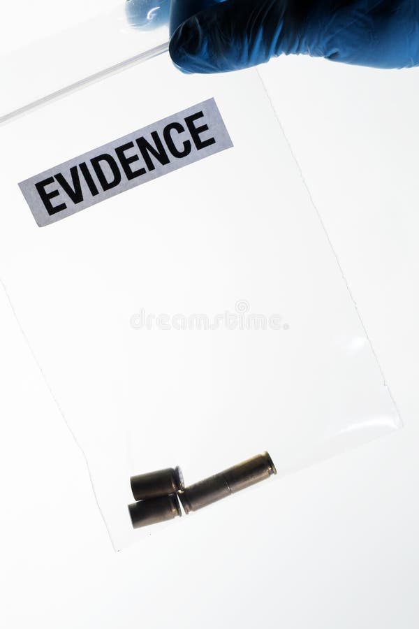 Cajas de la bala en el bolso de las pruebas sostenido por la mano con guantes del científico forense azul foto de archivo libre de regalías Cajas de la bala en el bolso de las pruebas sostenido por la mano con guantes del científico forense azul foto de archivo libre de regalías