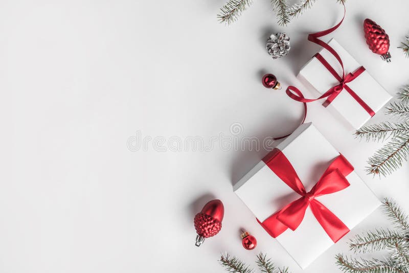 Cajas de regalo de la Navidad en el fondo blanco con las ramas del abeto, conos del pino, decoración roja