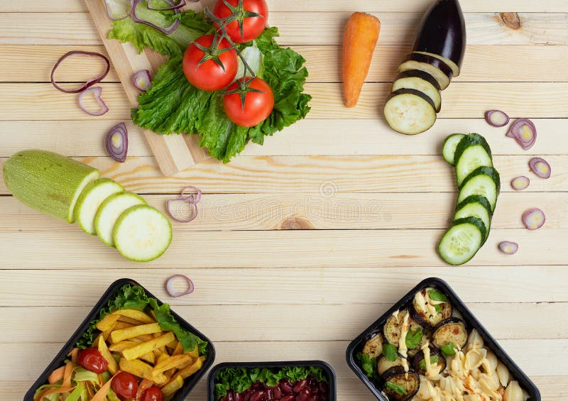 Cajas del envase de comida con la comida lista a comer, verduras crudas, zuchini y berenjenas, zanahoria y cebolla, lugar para el foto de archivo Cajas del envase de comida con la comida lista a comer, verduras crudas, zuchini y berenjenas, zanahoria y cebolla, lugar para el foto de archivo