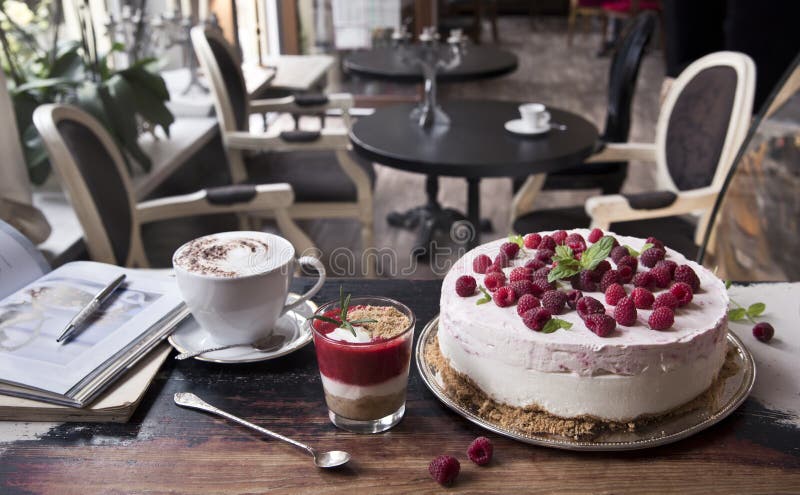 Cake met frambozen, koffie latte, aardbeidessert en boek op een oude lijst in retro koffie stock foto Cake met frambozen, koffie latte, aardbeidessert en boek op een oude lijst in retro koffie stock foto