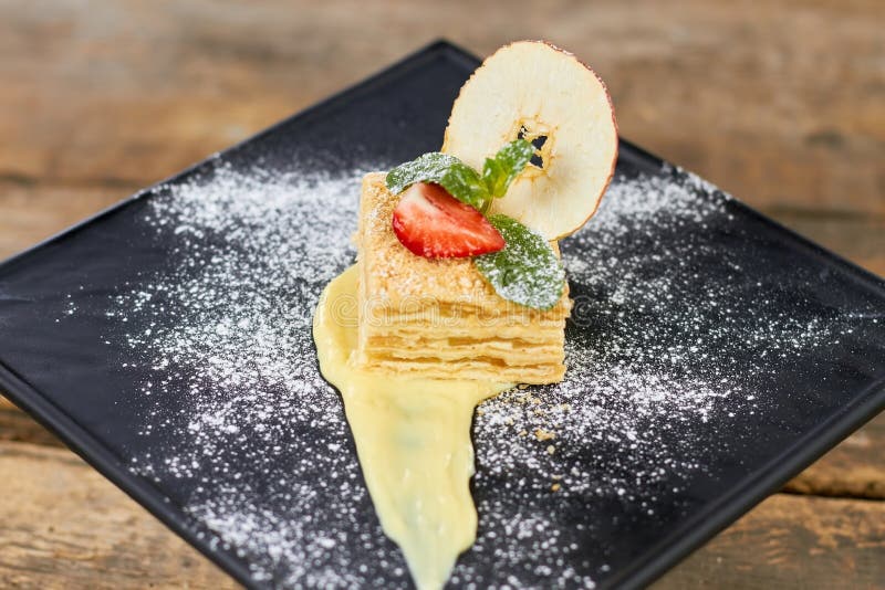 Cake Napoleon of puff pastry with sour cream on a black plate. stock images Cake Napoleon of puff pastry with sour cream on a black plate. stock images