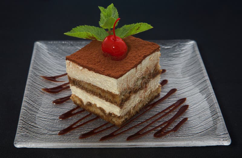 Tiramisu cake with mint and cherry on plate. Tiramisu cake with mint and cherry on plate