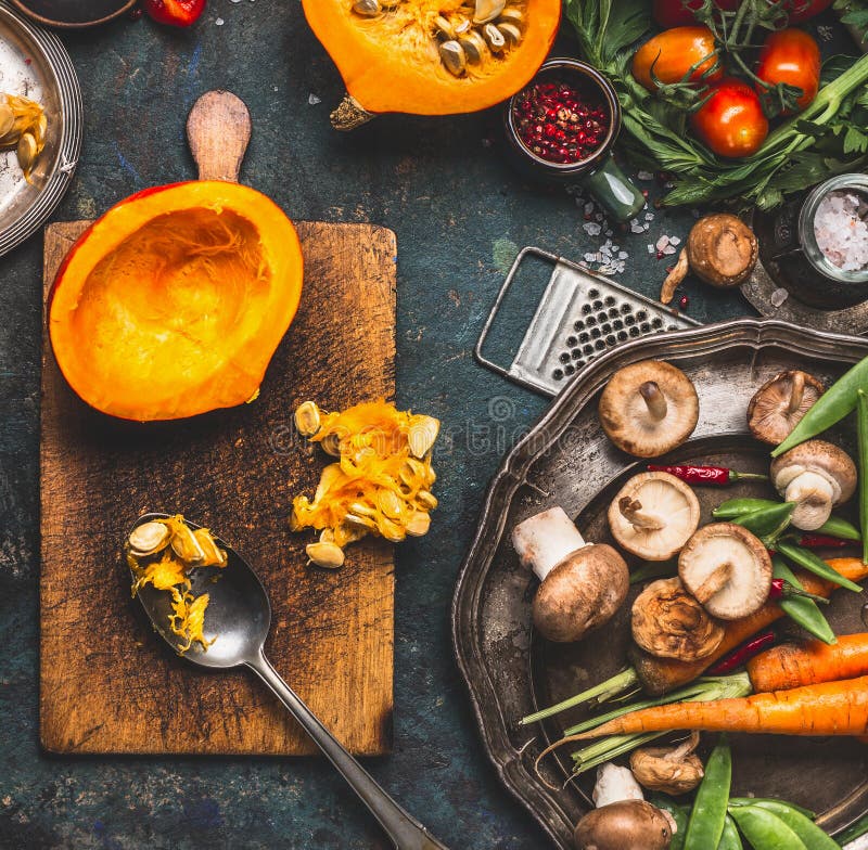 Calabaza media en tabla de cortar con la cuchara, las setas y los ingredientes de las verduras para cocinar vegetariano sabroso imagen de archivo Calabaza media en tabla de cortar con la cuchara, las setas y los ingredientes de las verduras para cocinar vegetariano sabroso imagen de archivo