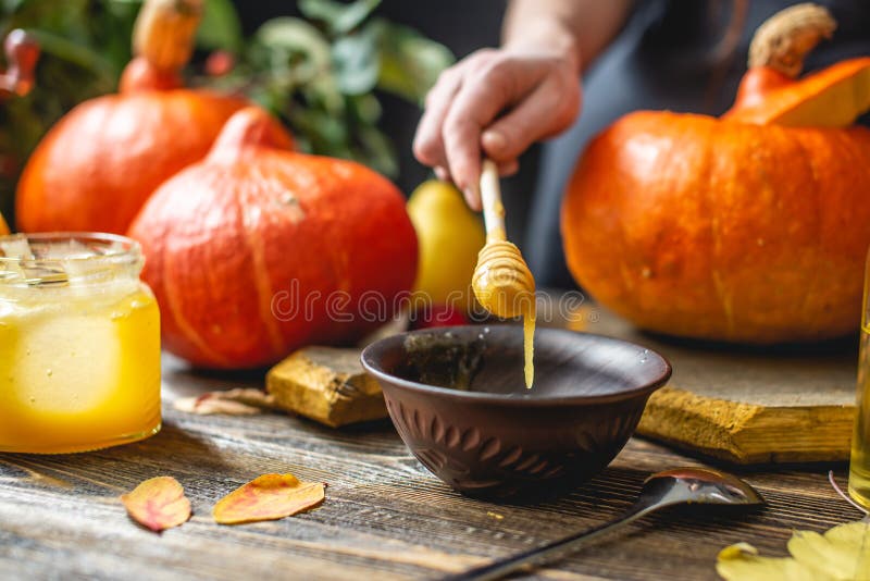 Calabazas naranjas para hornear con miel y canela sobre fondo de mesa de madera Concepto de comida otoñal imagen de archivo