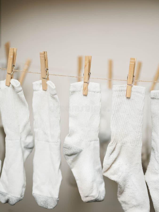 White socks clipped to rope to air dry indoors to save money on energy costs. Vertical image. White socks clipped to rope to air dry indoors to save money on energy costs. Vertical image