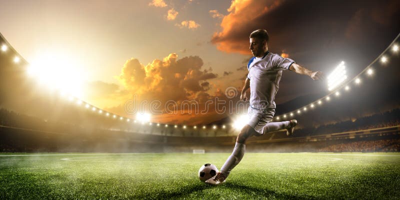 Calciatore nell'azione sul fondo di panorama dello stadio di tramonto fotografie stock libere da diritti Calciatore nell'azione sul fondo di panorama dello stadio di tramonto fotografie stock libere da diritti