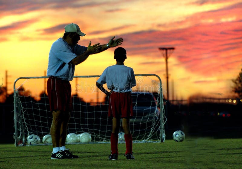 Calcio che istruisce al tramonto fotografia stock libera da diritti Calcio che istruisce al tramonto fotografia stock libera da diritti