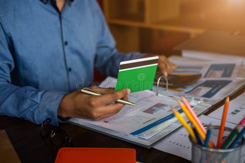 Calcolatore di uso dell'uomo d'affari per controllare qualcosa in libro contabile fotografia stock Calcolatore di uso dell'uomo d'affari per controllare qualcosa in libro contabile fotografia stock