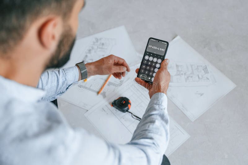 Calcolo dei numeri mediante smartphone. il piano è sul pavimento. l'uomo sta riparando nell'appartamento fotografie stock
