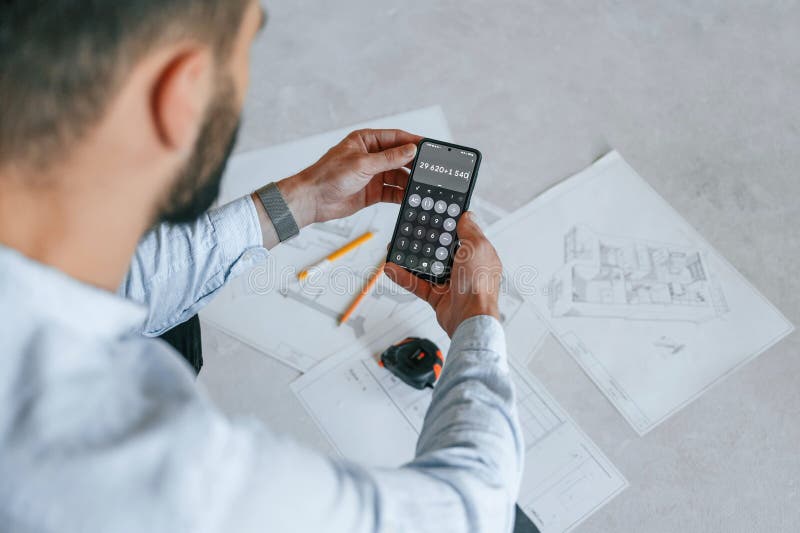 Calcolo dei numeri mediante smartphone. il piano è sul pavimento. l'uomo sta riparando nell'appartamento immagini stock libere da diritti