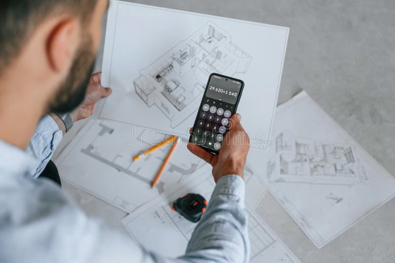 Calcolo dei numeri mediante smartphone. il piano è sul pavimento. l'uomo sta riparando nell'appartamento immagine stock