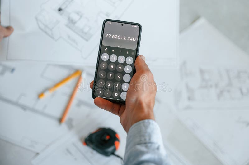 Calcolo dei numeri mediante smartphone. il piano è sul pavimento. l'uomo sta riparando nell'appartamento immagini stock libere da diritti