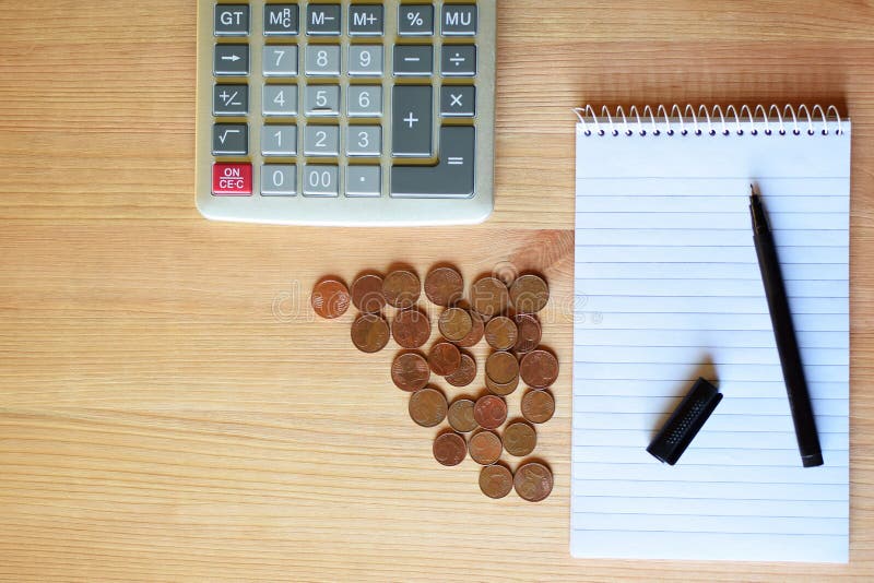 Calculator, blank notebook, pen and coins