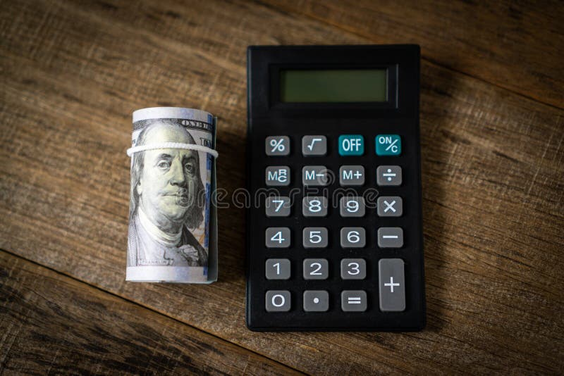 A calculator and a roll of dollar banknote stock photos