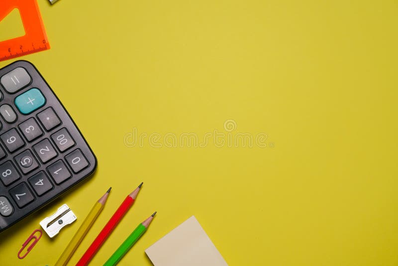 Calculator and stationery in different colors on a yellow background with copy royalty free stock image