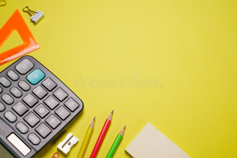 Calculator and stationery in different colors on a yellow background with copy space