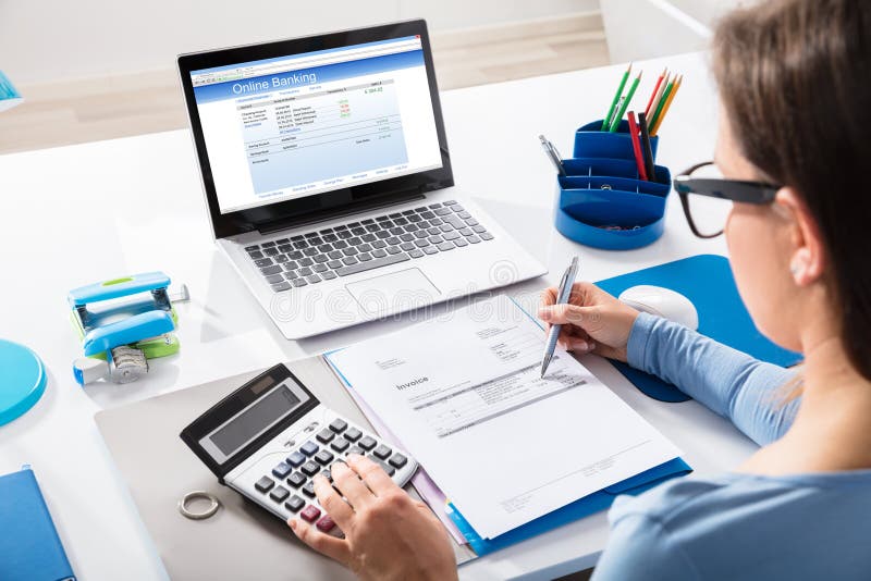 Close-up Of A Businesswoman Calculating Invoice Using Calculator With Online Banking On Laptop Screen. Close-up Of A Businesswoman Calculating Invoice Using Calculator With Online Banking On Laptop Screen