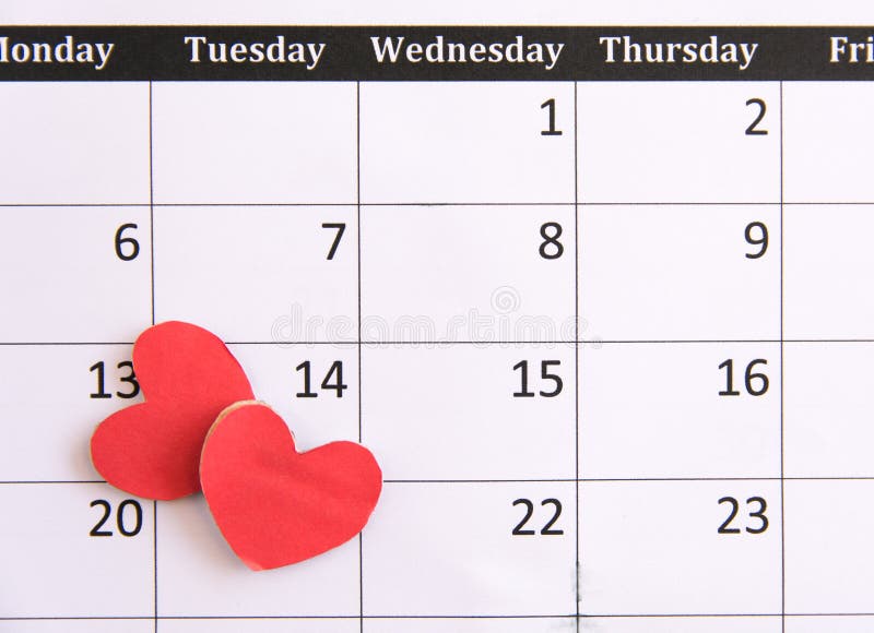 Calendar page and red hearts paper on February 14 of Valentines day.