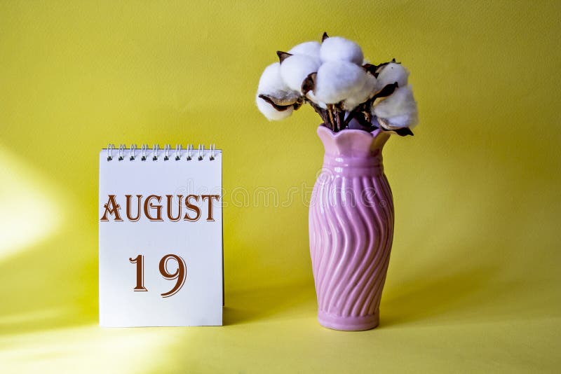 Calendar and Vase with Flower on Table Against Color Background, Space