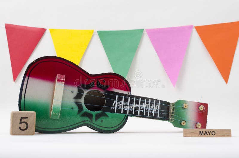 Calendário de madeira do cubo com data de Cinco de Mayo, guitarra do brinquedo e as bandeiras coloridas Calendário de madeira do cubo com data de Cinco de Mayo, guitarra do brinquedo e as bandeiras coloridas