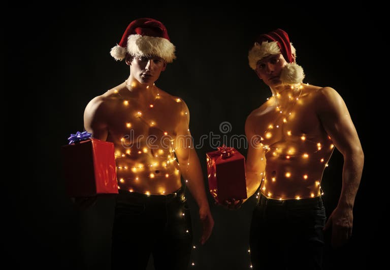 Call boys or athlete men at xmas. Christmas party and sex games. New year strip and gifts for adults. Young men in santa costume, present for girls. Twins santa with muscular body in garland.