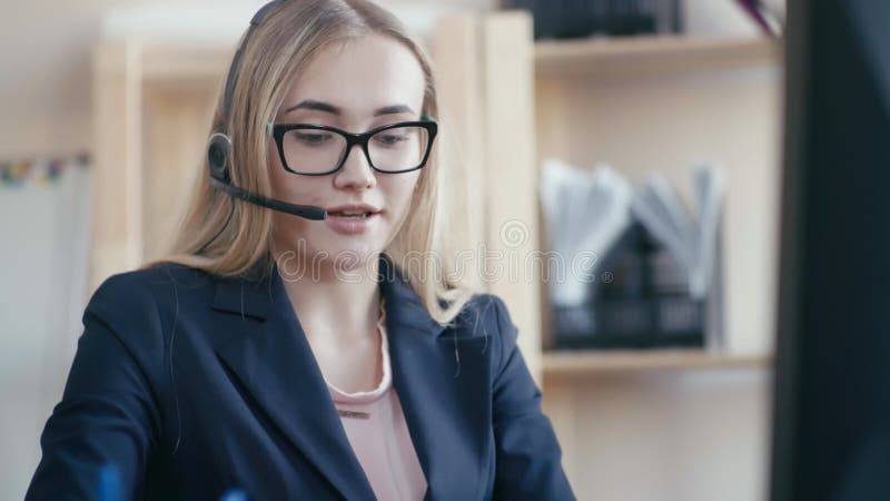Call center employee at work in the office. A young girl with blond hair with glasses sitting at a table in the office