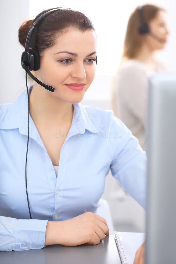 Call centreexploitant in hoofdtelefoon Jonge onderneemsterzitting bij bureau en terwijl het raadplegen van cliënten De klantendie stock afbeelding Call centreexploitant in hoofdtelefoon Jonge onderneemsterzitting bij bureau en terwijl het raadplegen van cliënten De klantendie stock afbeelding