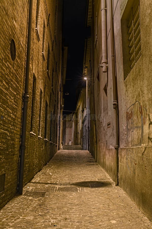 Narrow dark alley in the old town - old distressed alleyway in the italian city - grunge aged street at night. Narrow dark alley in the old town - old distressed alleyway in the italian city - grunge aged street at night