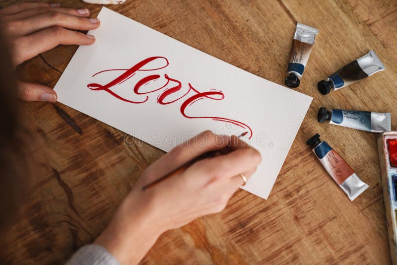 Calligrapher-skrivning när arbete pågår med valentiner vid bordsinomhus royaltyfria bilder