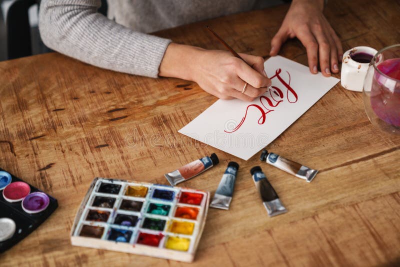 Calligrapher-skrivning när arbete pågår med valentiner vid bordsinomhus arkivbild
