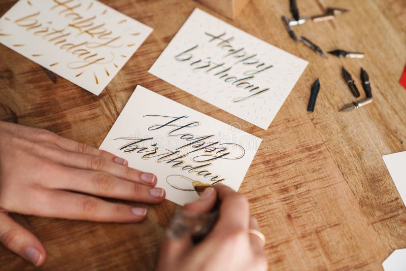 Calligrapher-skrivning när arbete utförs vid bord inomhus royaltyfria bilder