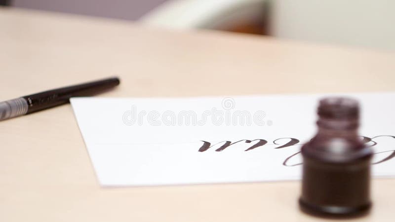 Calligraphic tools on beige table. Close shot. Side view. Camera moves along the desk with open inkpot and brush pen