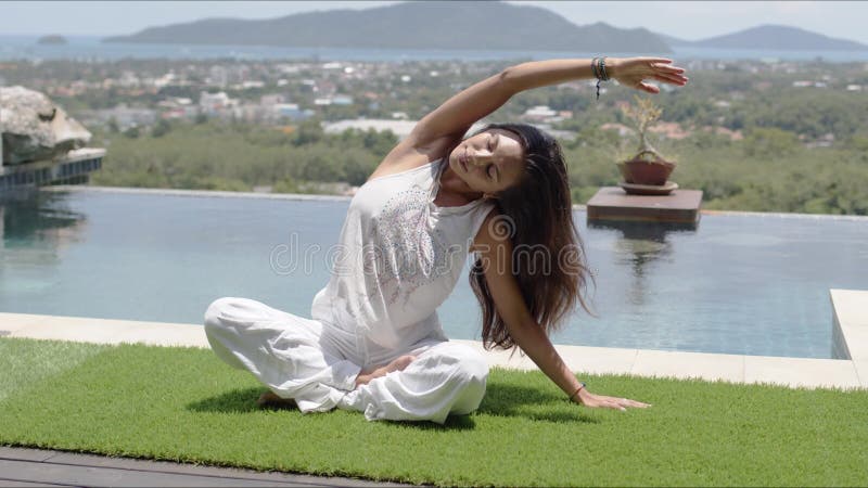 Relaxed barefooted lady sitting in lotus position near swimming pool