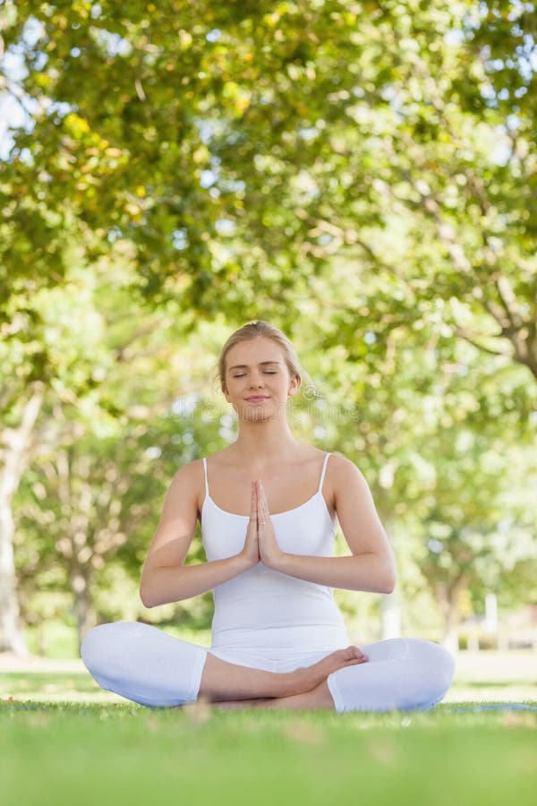 Calm beautiful woman meditating sitting in a park