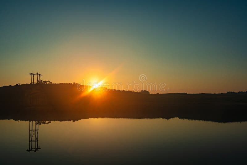 Calm lake with dramatic sunrise orange sky reflection at morning sunrise over mountain shadow and calm lake with reflection at morning from flat angle