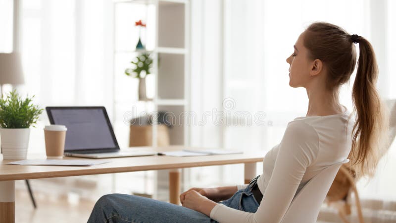 Calm young woman relaxing with closed eyes in chair at workplace