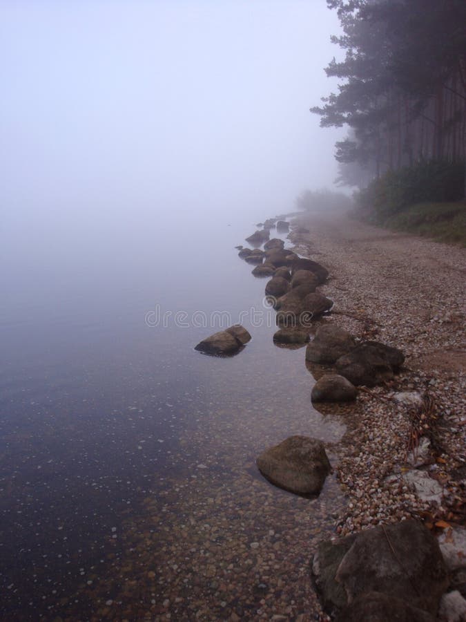 Calm water white and blue tones flowing over smooth rocks at the lake shore