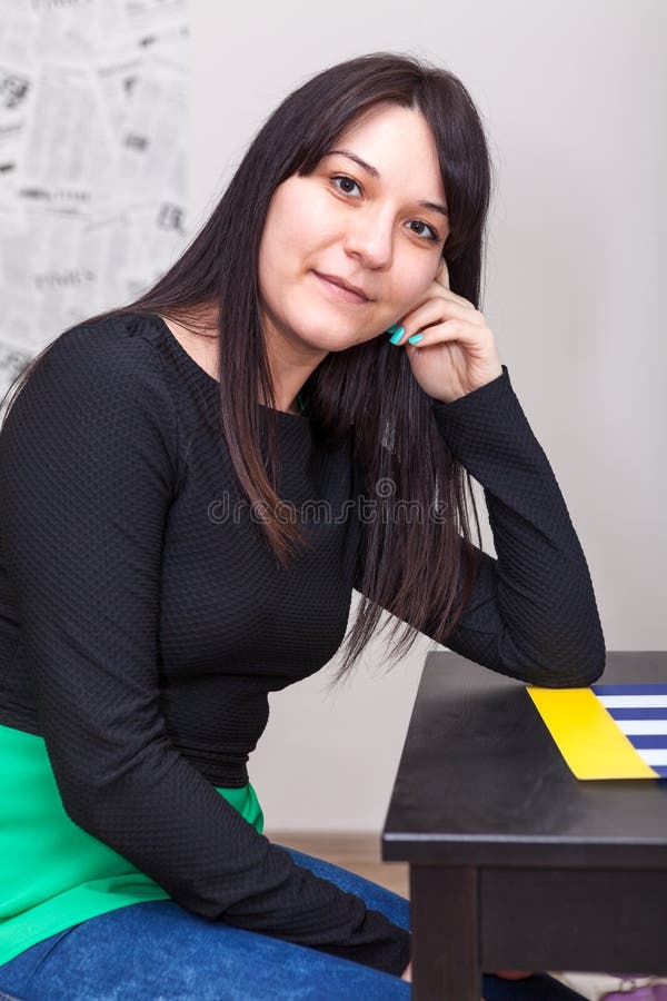 Calm young woman sitting at table, long dark hair stock image Calm young woman sitting at table, long dark hair stock image