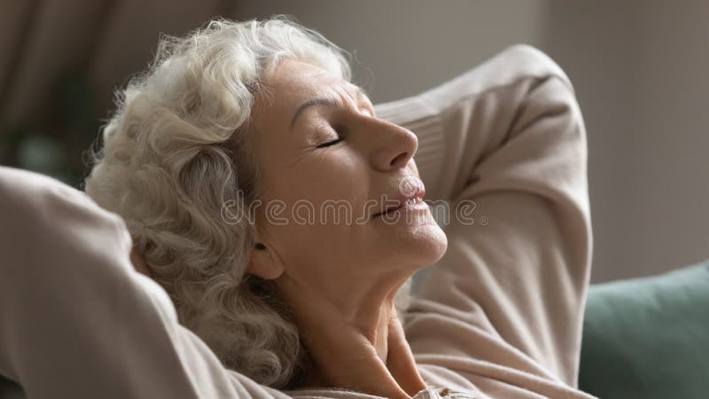 Calma donna anziana rilassata sul divano che respira aria fresca