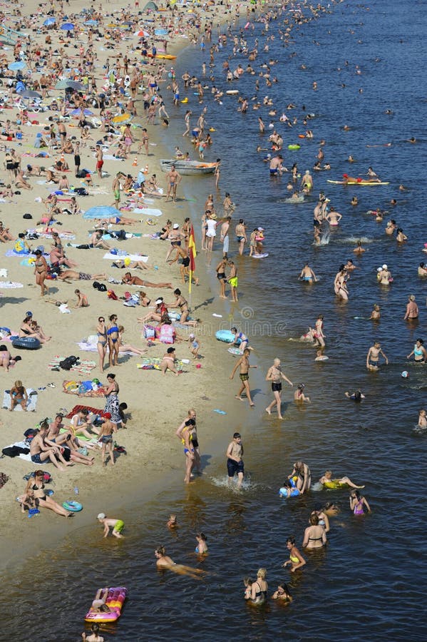 Calor Fuerte En La Playa. Multitud De Personas Tomando El Sol Y Nadando