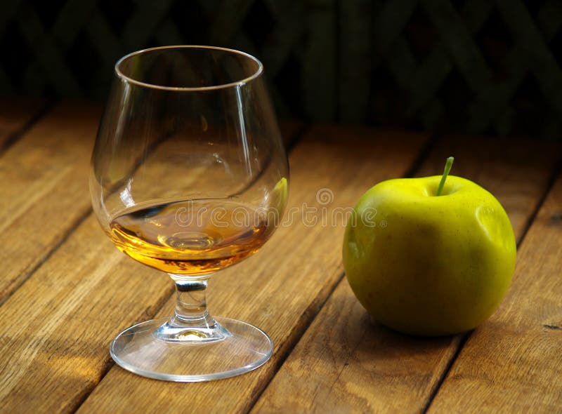 Green apple and glass of calvados jn the wooden table