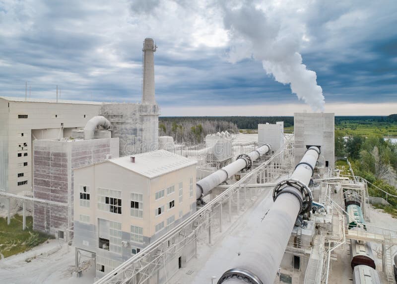 Calx roasting rotating furnace with pipe and rising steam at manufacturing plant against cloudy sky aerial view. Limestone hot processing. Calx roasting rotating furnace with pipe and rising steam at manufacturing plant against cloudy sky aerial view. Limestone hot processing