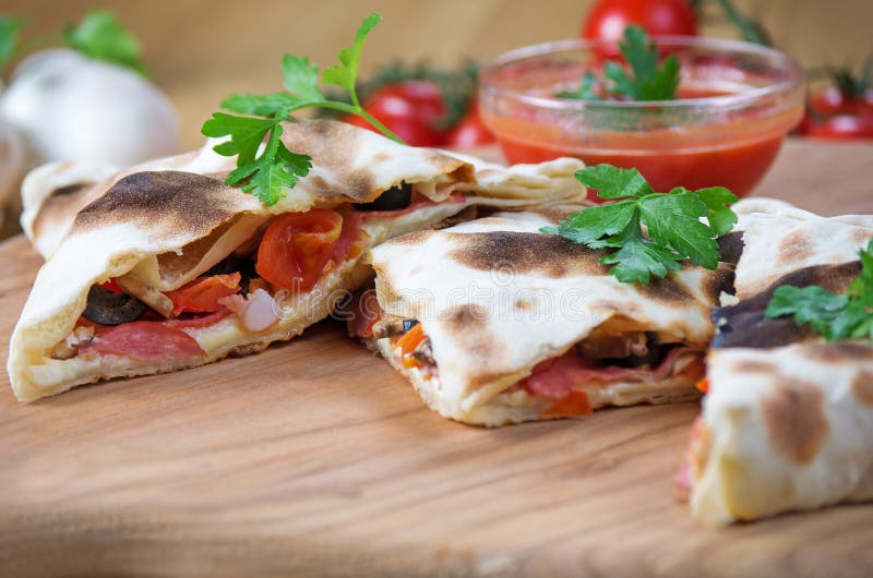 Pizza calzone in the form of cutting with close up on a wooden background. Pizza calzone in the form of cutting with close up on a wooden background