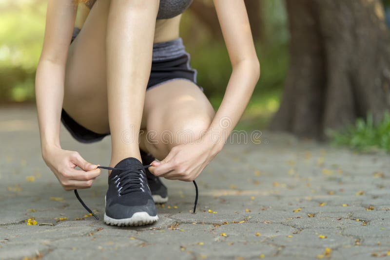 Calçados de corrida - Cadarços de sapato amarrados por mulheres Cantora do esporte feminino que se prepara para correr no jardim fotos de stock Calçados de corrida - Cadarços de sapato amarrados por mulheres Cantora do esporte feminino que se prepara para correr no jardim fotos de stock