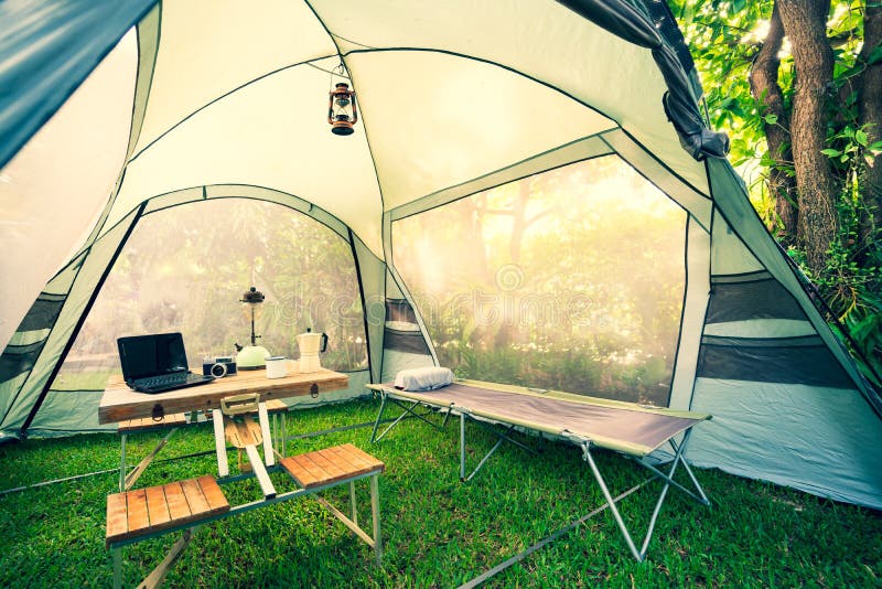 Cama Plegable Dentro De La Carpa En Las Lámparas De Aceite De La Mañana Y  En El Café Pone Cuadernos En Una Mesa De Camping De Made Imagen de archivo  - Imagen